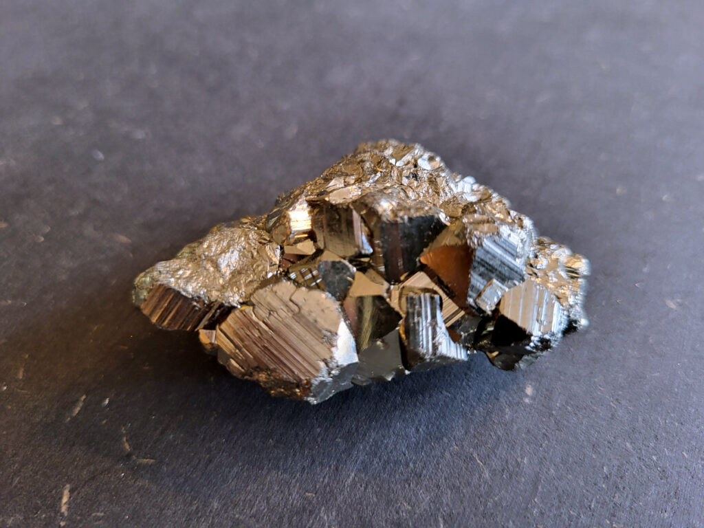 Pyriet, tussen 3,- en 6,- euro, nr. 7

Pyriet, beschrijving
Pyriet, ook wel bekend als klatergoud. Het is een mineraal van ijzer en zwavel met een goudgele, metaalachtige glans, wat het soms doet lijken op goud. De naam komt van het Griekse woord voor 'vuur' ,
omdat het vonken geeft als je het ergens tegenaan slaat. Het wordt industrieel gebruikt voor de productie van zwavelzuur en als decoratieve steen, terwijl het in de oudheid diende als vuursteen.
Kenmerken
Uiterlijk: Goudgeel met een metaalachtige glans. De kristallen zijn vaak kubusvormig, maar kunnen ook andere vormen hebben.
Naam: Afgeleid van het Griekse woord voor 'vuur', vanwege het vonkend effect bij impact.
Bijnaam: Ook wel "klatergoud" of "goud der dwazen" genoemd vanwege de gelijkenis met echt goud.
Toepassingen en gebruik
Industrie: Het is een belangrijke bron voor de productie van zwavelzuur, dat onder andere wordt gebruikt in kunstmest en olieraffinage.
Geschiedenis: In de oudheid werd het gebruikt als vuursteen om vuur te maken.
Decoratie en sieraden: Vanwege zijn goudachtige uiterlijk wordt het veel gebruikt in sieraden en decoratieve objecten.
Wetenschap: Het dient als indicator voor geologische processen en wordt gebruikt in mineralogisch onderzoek.
Onderscheid met goud
Textuur: Ruwe pyrietkristallen hebben scherpere randen dan ruw goud.
Kleur: Pyriet heeft vaker een koperachtige tint, terwijl echt goud een helderder, geelgouden kleur heeft.
Hardheid: Pyriet is harder dan goud (hardheid van 6-6,5 versus 2,5).
Dichtheid: Pyriet is lichter in gewicht dan goud.