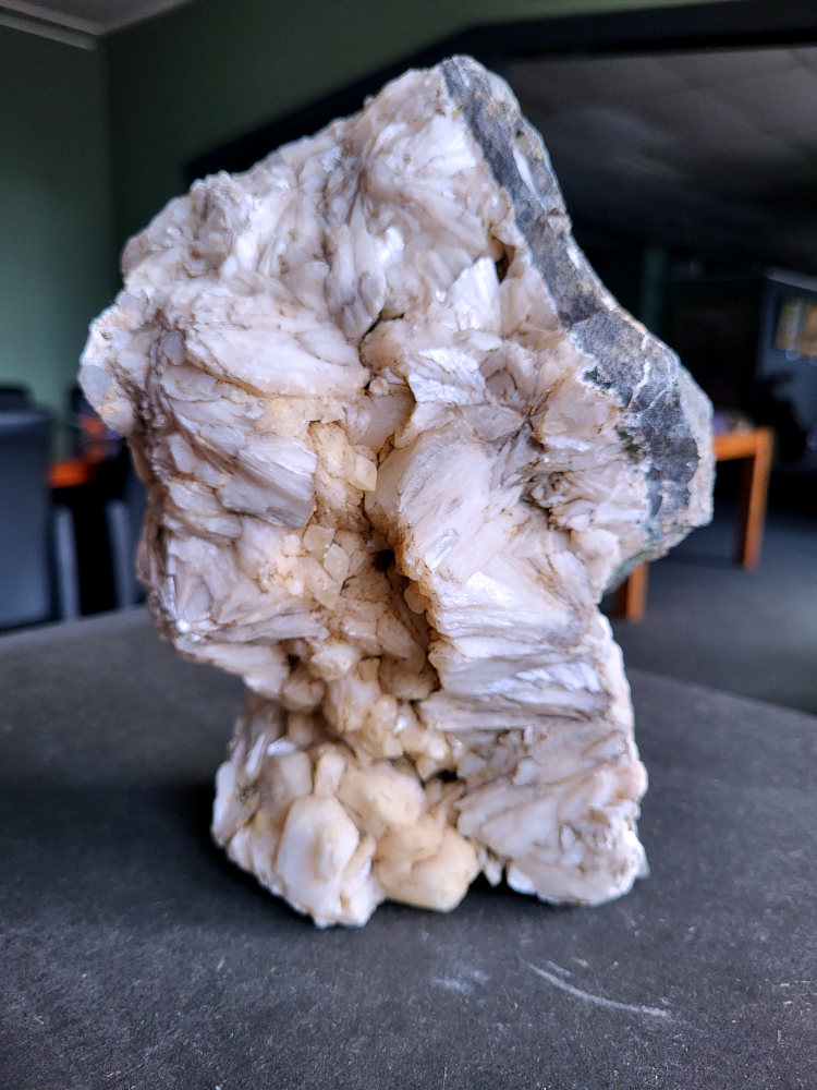 Stilbiet en Calciet, 3 kg, 35 euro, nr. 60

Stilbiet, beschrijving,
Stilbiet,
De waaier- of bundelvormige kristallen met een zijdeachtige glans en soms lichtgroen-geelatige gloed zijn typisch voor stilbiet.
De helder witte tot doorschijnende kubusvormige kristallen aan de basis zijn apofyliet.
De gele of groenige zweem kan komen van een lichte epidoot- of prehniet-insluiting, of een natuurlijke oxidatie aan het oppervlak.
Energetische werking:
Stilbiet opent het hart en helpt loslaten van zorgen; het is zacht, troostend en bevordert vertrouwen in de loop van het leven.
Apofyliet versterkt intuïtie, helderheid en spirituele verbinding — een “lichtbrenger” die energie zuivert in een ruimte.
Samen vormen ze een kalmerende, hoogtrillende combinatie die ideaal is voor meditatie, healingruimtes of slaapkamers (voor rust en inzicht).
Zorgtip:
Houd ze uit direct zonlicht (kan verkleuren) en reinig liever met klank, maanlicht of wierook in plaats van water — apofyliet lost iets op bij langdurig vocht.
Uiterlijk:
De perzik- tot crème-witte kleur,
De glanzende, waaier- of bloemvormige kristalstructuur,
De zachte, zijdeachtige glans (bijna parelmoerachtig),
al die kenmerken passen heel goed bij stilbiet.
De ronde, lichtgrijze korrelige bol bovenop kan een heulandiet- of chalcedoon-vorming zijn die samen met de stilbiet is gegroeid.
Energetische betekenis:
Stilbiet hoort bij het hart en het kruinchakra — een zachte, troostende energie die helpt bij het loslaten van oude patronen en het verbinden met hogere leiding.
Ze ondersteunt intuïtie, dromen en zachtheid in relaties — een heel liefdevolle steen om in huis te hebben, vooral bij healing- of slaapruimtes.