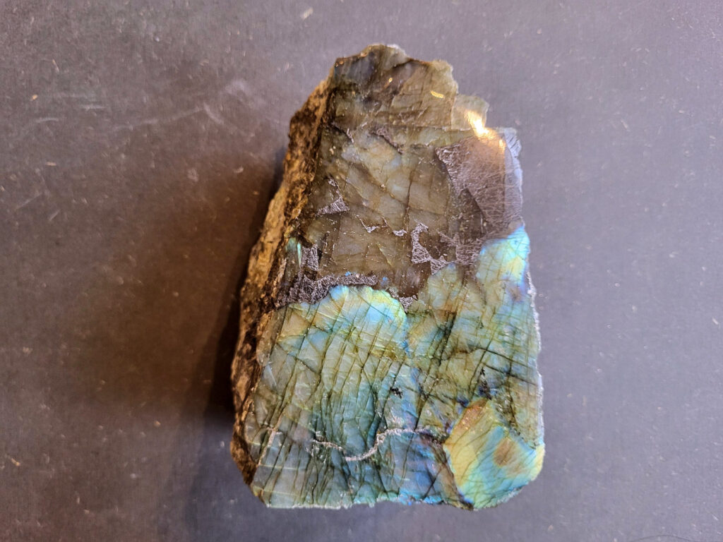 Labradoriet half gepolijst, 1,8kg, 15hx11bx7d, 55 euro, foto 2, nr. 6

Labradoriet, beschrijving
Labradoriet is een edelsteen die bekend staat om zijn iriserende kleurenspel, ook wel labradoriseren genoemd, dat vaak doet denken aan het noorderlicht. Het is een populaire steen in de edelstenenwereld vanwege zowel zijn uiterlijk als zijn vermeende spirituele eigenschappen.
Wat is labradoriet?
Labradoriet is een veldspaatmineraal dat wordt gekenmerkt door een opaalachtig glans of iriserend effect, veroorzaakt door de lichtbreking in de interne structuur van de steen.
De meest voorkomende kleur is grijs of groenachtig grijs, maar de steen kan ook blauwe, gele, oranje, paarse of zelfs rode flitsen laten zien.
De steen is genoemd naar het Canadese schiereiland Labrador, waar het voor het eerst werd ontdekt.
Spirituele betekenis en eigenschappen:
Labradoriet wordt vaak beschouwd als een beschermende steen, vooral voor mensen die gevoelig zijn voor de energieën van hun omgeving.
Het zou helpen bij het versterken van de aura en het verminderen van energielekkage, waardoor je je weerbaarder voelt.
Labradoriet wordt geassocieerd met het versterken van intuïtie, het vergroten van het bewustzijn en het transformeren van negatieve energieën.
Het wordt ook gebruikt om blokkades op te heffen en de innerlijke wijsheid te onthullen.
Gebruik:
Labradoriet wordt vaak verwerkt in sieraden zoals hangers, armbanden en oorbellen.
Het kan ook als ruwe steen, knuffelsteen of in andere vormen worden gebruikt, bijvoorbeeld in een huis of op een werkplek.
Labradoriet kan worden gereinigd door het onder stromend water te houden of door het te reinigen met een andere steen zoals bergkristal of seleniet.
Vindplaatsen:
Labradoriet wordt gevonden op verschillende locaties over de hele wereld, waaronder Canada, Finland, Madagaskar en Rusland.
-Kunstgalerie Arnold-
